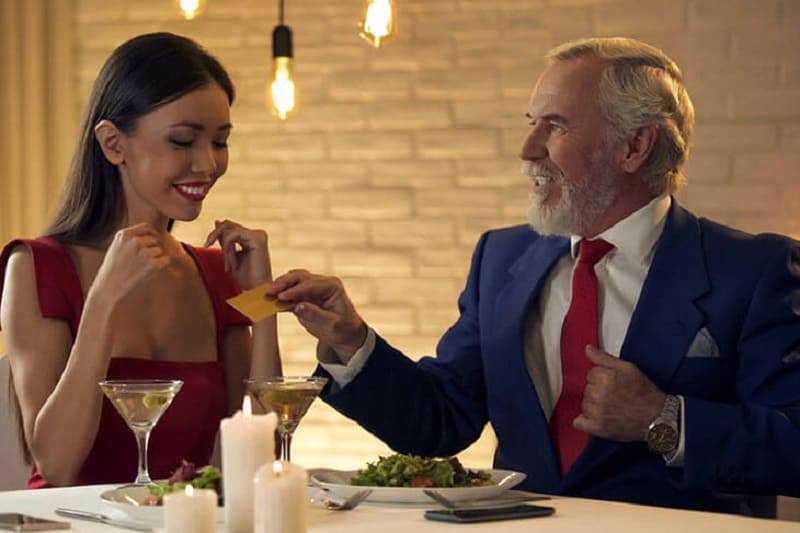 sugar daddy giving his gold card to a young woman